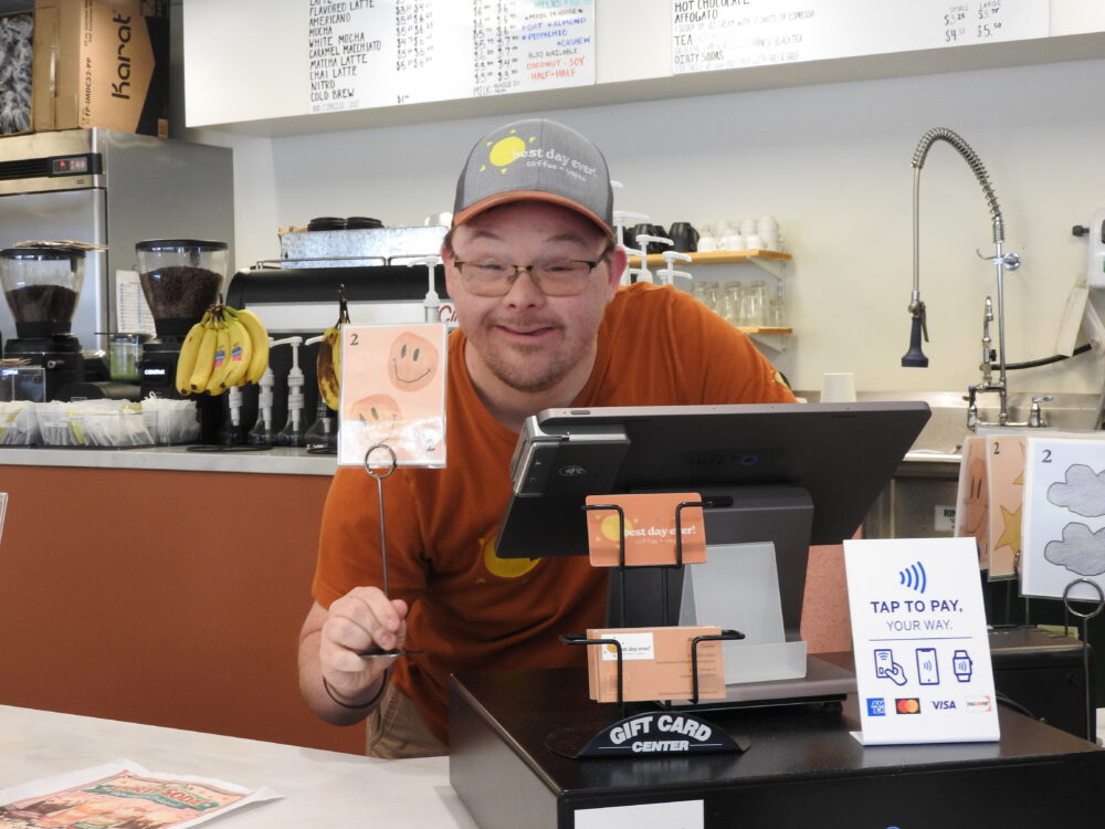 Seth smiling behind the counter at the Best Day Ever coffee and crepes shop